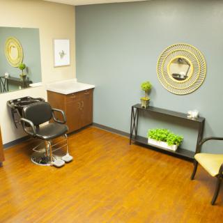 A well-organized salon room featuring a hairdressing chair, mirror, and decorative elements.