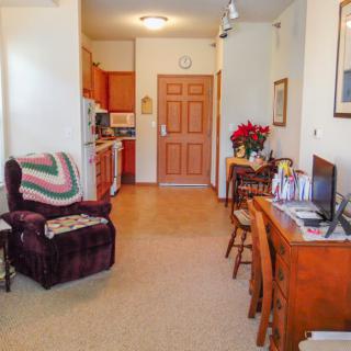 A cozy living space with an armchair, desk, and view into the kitchen.