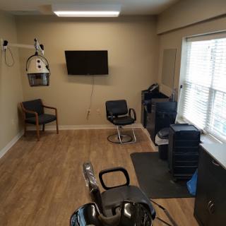 A minimalistic hair salon setup featuring a waiting area, a barber chair, and essential equipment for hair styling.