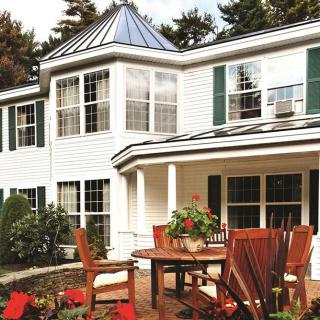 A beautiful house with a patio featuring outdoor furniture and potted plants.