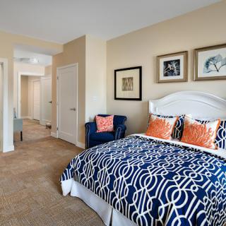 A well-decorated bedroom featuring a bed with a patterned blue and white duvet, colorful pillows, and wall art.