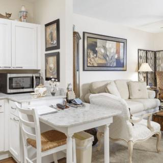 A cozy open-concept kitchen and living room with a white color scheme and elegant decor.