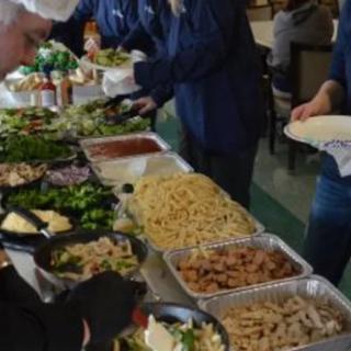 People serving themselves from a buffet with a variety of dishes.