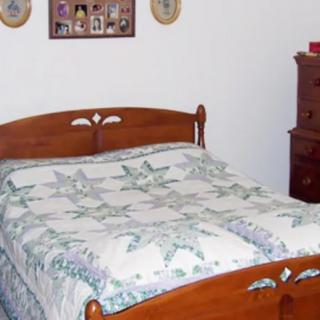A cozy bedroom featuring a wooden bed with a patterned quilt and a matching dresser.
