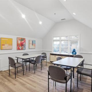 A modern, well-lit meeting room featuring tables and chairs, adorned with colorful artwork on the walls.