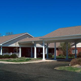 A welcoming residential building with a spacious front entrance and well-maintained landscaping under a clear blue sky.