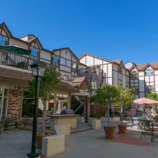 A courtyard with seating and umbrellas in front of a multi-story building.