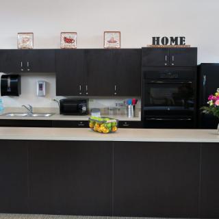A modern kitchen with dark cabinets, a countertop featuring a fruit bowl, and decorative elements.