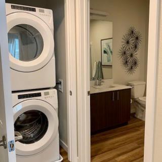 A modern home laundry area with a stacked washer and dryer, adjacent to a bathroom with contemporary decor.