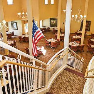 A spacious dining area with elegant chandeliers and a prominent American flag, viewed from a staircase.