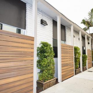 A modern building exterior featuring sleek wooden paneling and potted greenery.