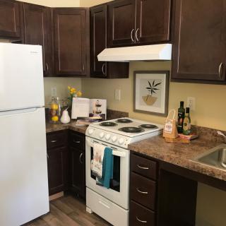 A cozy kitchen with dark cabinets and white appliances, including a fridge and stove.