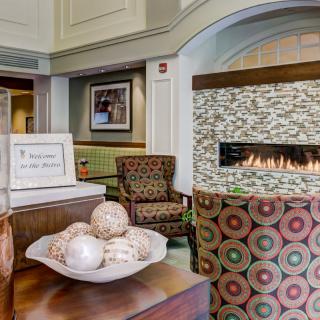 A cozy lobby interior featuring modern decor, a decorative fireplace, and comfortable seating.