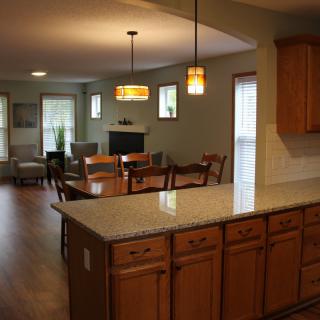 An open concept kitchen and living area with wooden cabinetry, an island, and modern lighting.