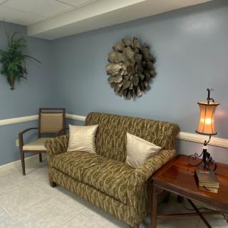 A cozy living room with a patterned sofa, decorative wall art, and a warm lamp.