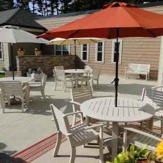 A sunny outdoor patio area featuring white furniture and colorful umbrellas, perfect for relaxation.