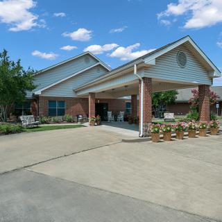 A suburban residential building with a covered entrance and landscaped surroundings.