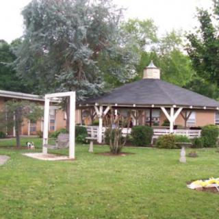 A beautiful garden setting with a gazebo surrounded by lush greenery and trees.