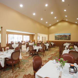 A spacious and elegantly decorated restaurant dining room with neatly arranged tables and chairs.