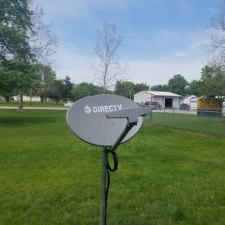 A satellite dish set up on a grassy lawn, with a clear sky in the background.