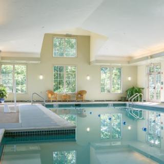 A serene indoor swimming pool surrounded by large windows, inviting natural light and a tranquil atmosphere.