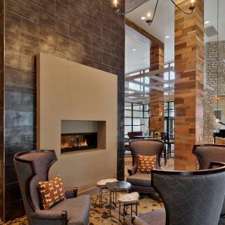 A modern lounge with a cozy seating area and fireplace, featuring elegant wood paneling.