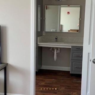 A view into a bathroom featuring a large mirror and sink with surrounding cabinets.