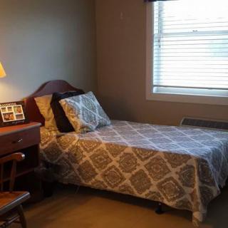 A cozy bedroom with a single bed, desk, and lamp by the window.