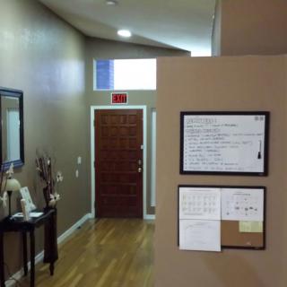 A hallway with a front door, wall decor, and a hardwood floor.