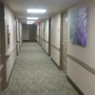 A well-lit hallway with doors on either side and artwork on the walls.