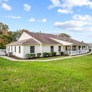 A single-story residential house with a well-maintained lawn under a partly cloudy sky.