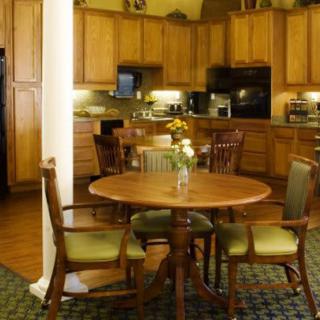 A cozy kitchen with wooden cabinets and a round dining table surrounded by chairs.