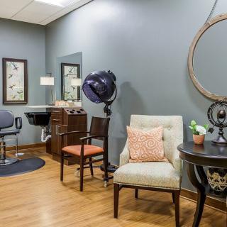 A cozy salon interior with seating, a hair dryer, and decorative elements.