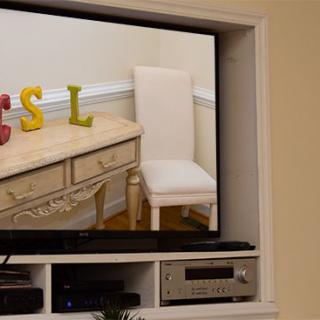 A television displaying decorative letters on a shelf in a living room setting.