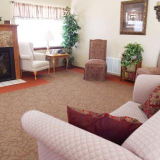 A cozy living room with a sofa, chairs, and a fireplace, complemented by indoor plants and decorative items.