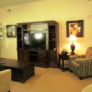 A cozy living room with a TV stand, armchairs, and decorative elements.