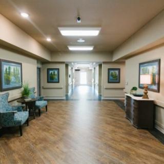 A well-decorated hallway with paintings, chairs, and wooden flooring.