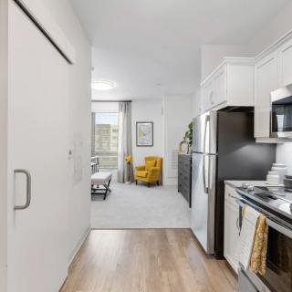 Modern apartment interior featuring an open kitchen leading to a cozy living area with a yellow chair.