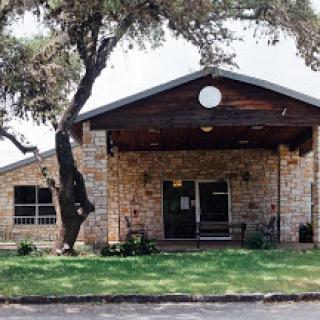 A charming stone and wood building surrounded by greenery, featuring a welcoming entrance.