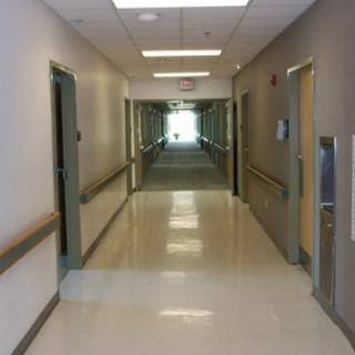 A view of a hospital hallway with doors on either side.