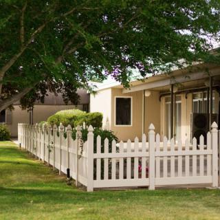 A house with a white picket fence and a neatly maintained lawn.