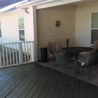 A cozy outdoor patio with a table and chairs set on a wooden deck.