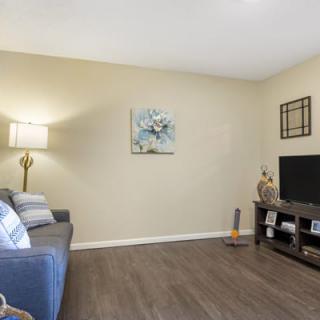 A cozy living room with a sofa, lamp, and television set on a wooden floor.