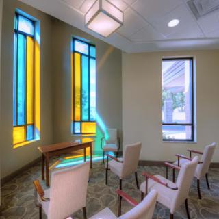 A serene waiting room featuring colorful stained glass windows and comfortable seating.