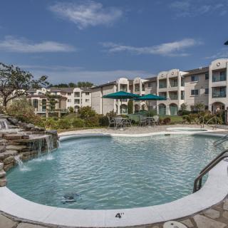 A scenic view of a swimming pool in a residential complex with apartment buildings in the background.