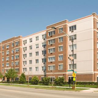 A modern apartment building with a brick and white facade, situated in an urban environment.