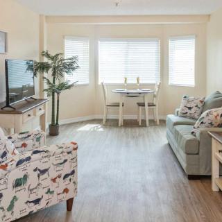 A cozy living room with a sofa, armchair, and dining area.