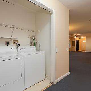 A small laundry area in an apartment hallway featuring a washer and dryer.