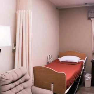 A neatly arranged hospital room featuring a single bed and a comfortable chair.