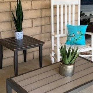 Cozy patio setup with a rocking chair, tables, and potted plants.
